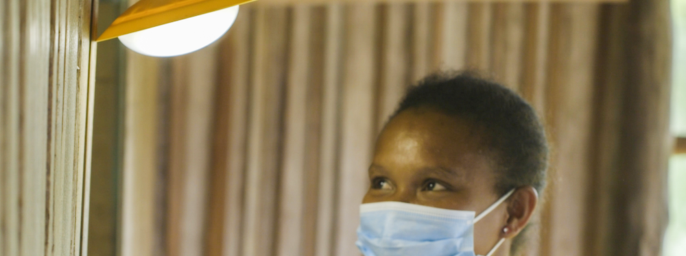 Woman with blue surgical mask looks at light