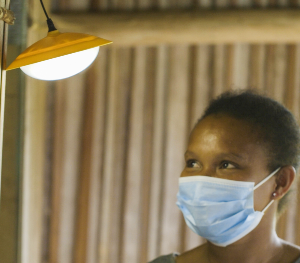 Woman with blue surgical mask looks at light