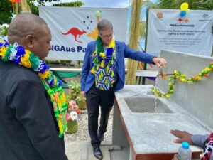 Australian High Commissioner in PNG turning on a tap in a celebration with community members.